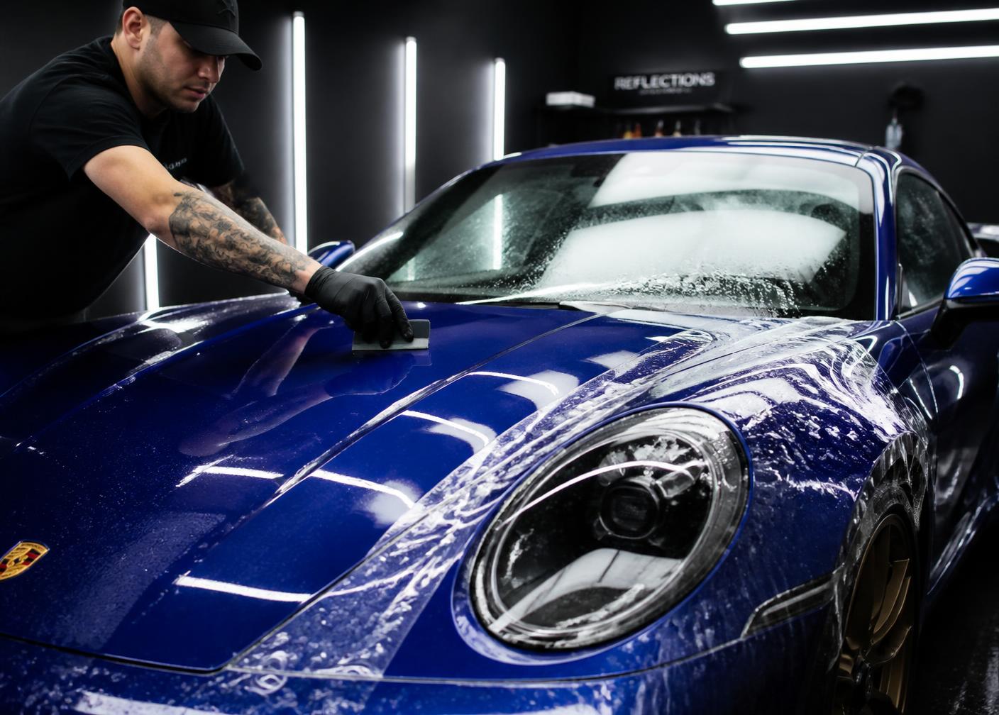 Aplicação profissional de película de proteção sobre a pintura de um carro escuro