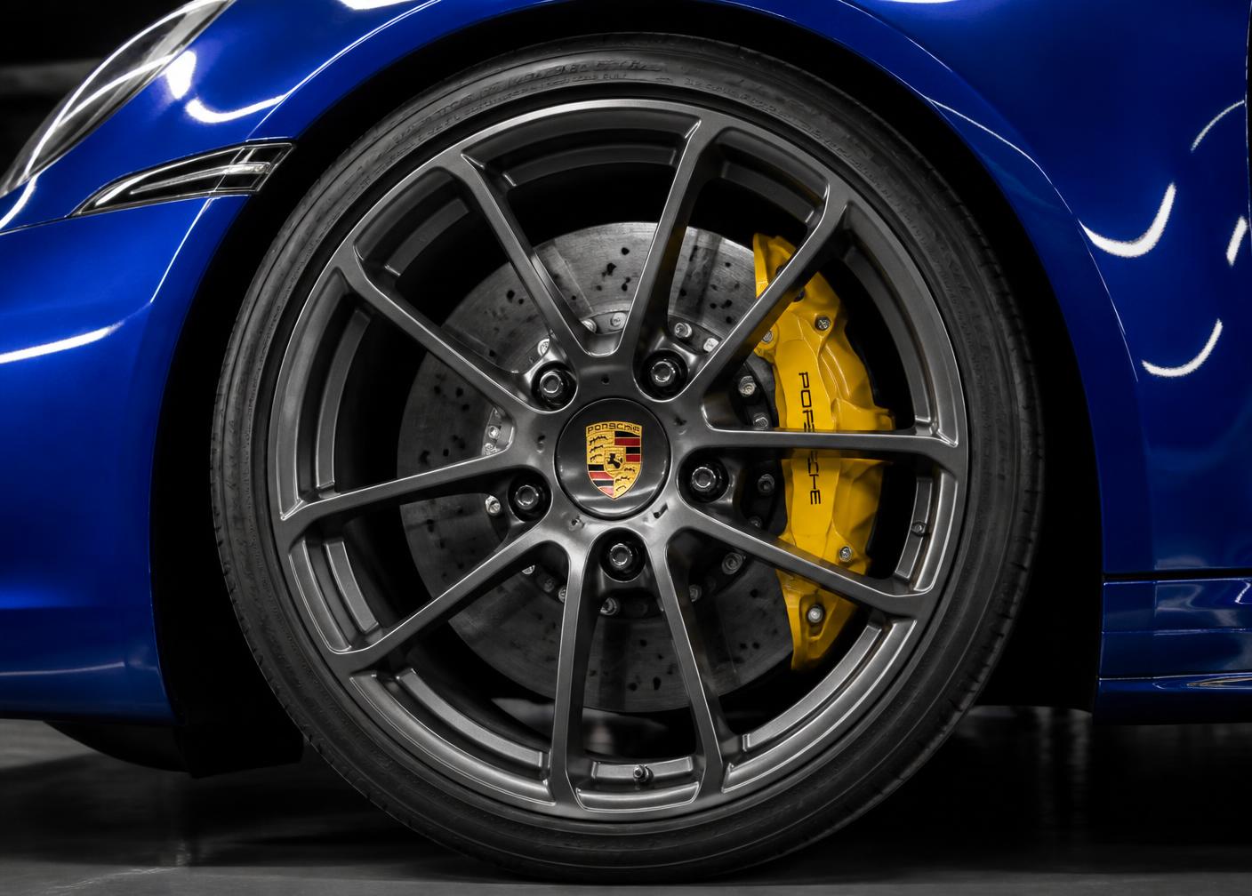 Roda Porsche escura com brasão central e pinça de freio amarela
